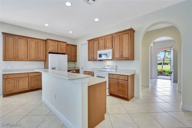 kitchen with light tile patterned floors, a kitchen island, and white appliances