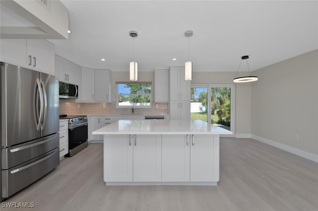 kitchen featuring appliances with stainless steel finishes, a kitchen island, white cabinetry, and hanging light fixtures