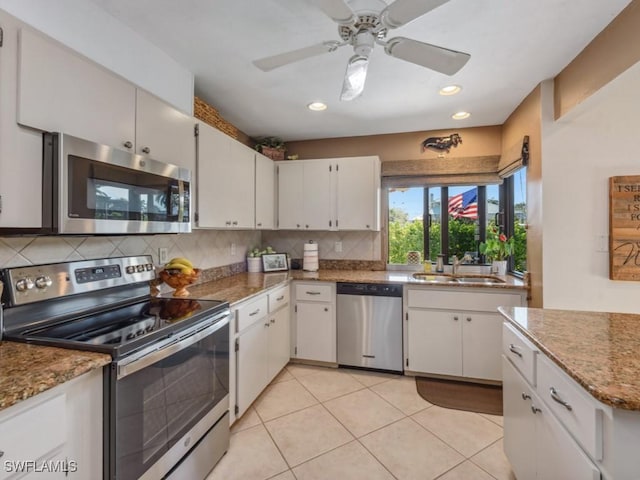 kitchen with sink, stainless steel appliances, white cabinets, light stone counters, and light tile patterned flooring