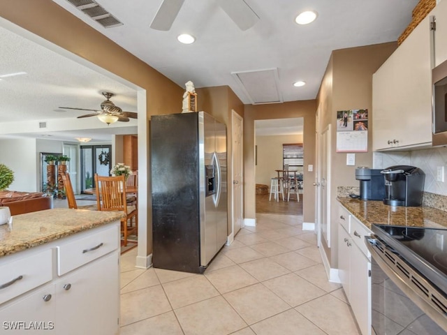 kitchen featuring light stone countertops, appliances with stainless steel finishes, decorative backsplash, light tile patterned floors, and white cabinetry