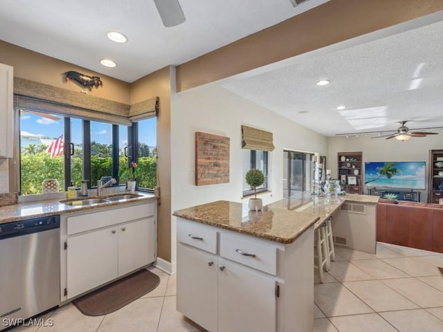 kitchen featuring light stone countertops, stainless steel dishwasher, a textured ceiling, sink, and white cabinets