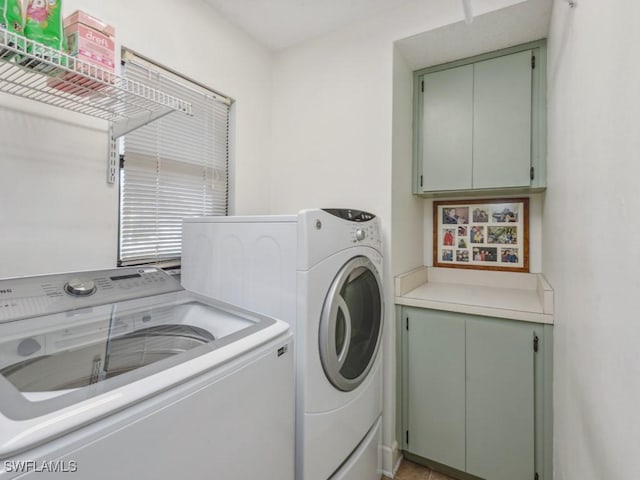 clothes washing area with washer and dryer and cabinets