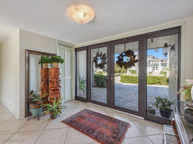 entrance foyer with french doors, light tile patterned floors, and a textured ceiling