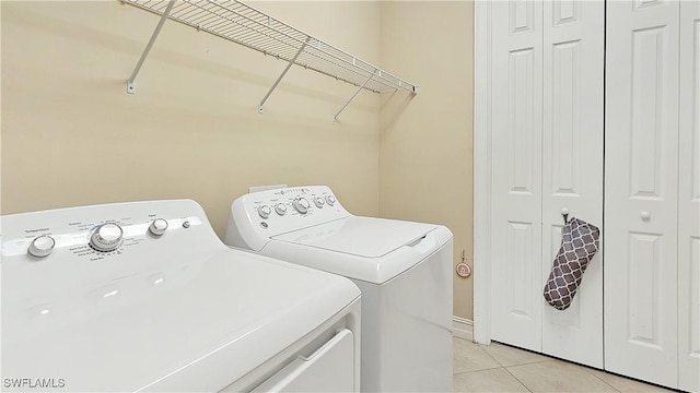 washroom with laundry area, washing machine and clothes dryer, and light tile patterned floors