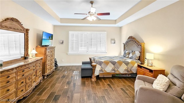 bedroom with baseboards, a raised ceiling, a ceiling fan, and wood finish floors