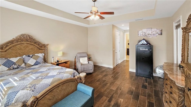 bedroom featuring dark wood-style floors, a raised ceiling, visible vents, and baseboards