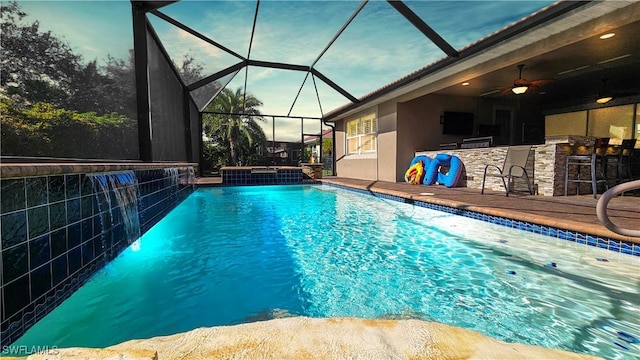 outdoor pool with glass enclosure, ceiling fan, and outdoor dry bar