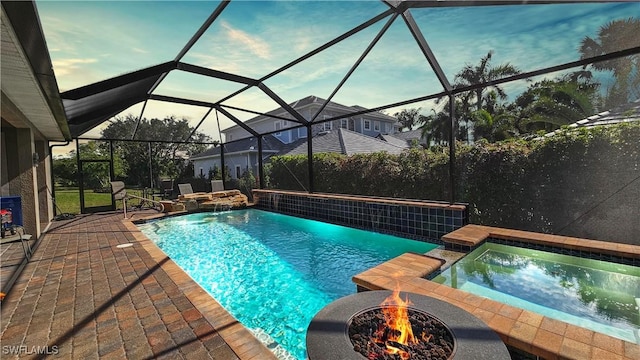 view of pool featuring a lanai, a patio area, a pool with connected hot tub, and a fire pit