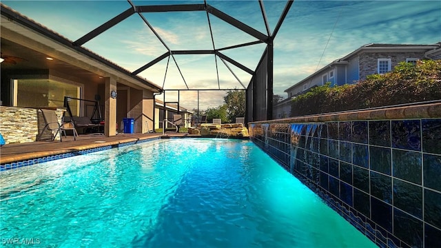 outdoor pool featuring glass enclosure and a ceiling fan