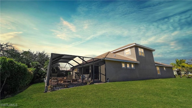 back of property with a lanai, stucco siding, a patio area, and a yard