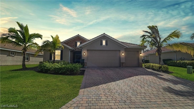 ranch-style house with an attached garage, decorative driveway, a lawn, and stucco siding