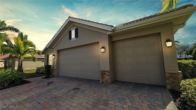 garage at dusk featuring decorative driveway