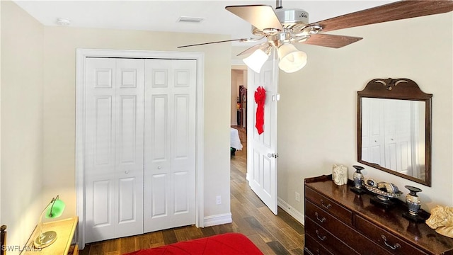 bedroom featuring a closet, dark wood-style flooring, baseboards, and a ceiling fan