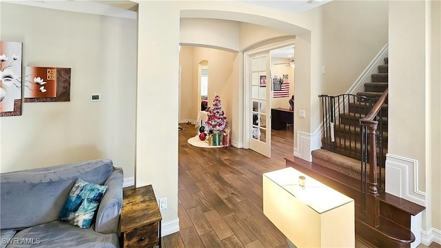 interior space featuring baseboards, stairs, arched walkways, and wood finished floors