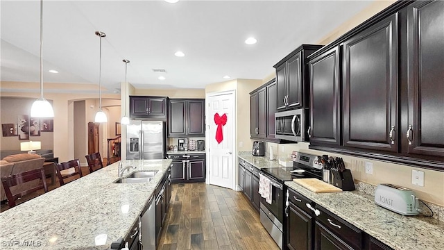 kitchen with light stone counters, stainless steel appliances, recessed lighting, dark wood-type flooring, and a sink