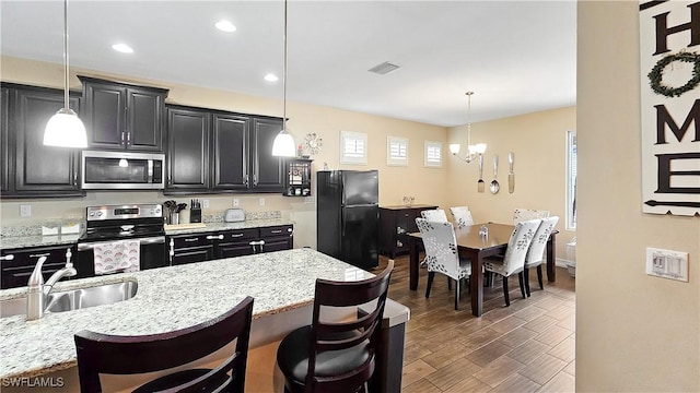 kitchen featuring a breakfast bar, visible vents, appliances with stainless steel finishes, wood finished floors, and dark cabinetry