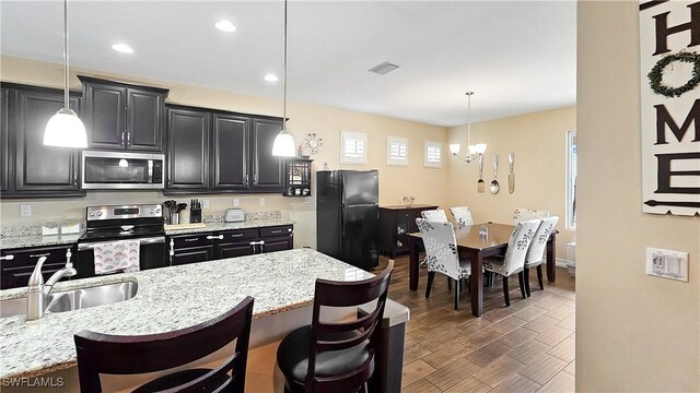 3240 Banyon Hollow Loop, North Fort Myers, FL 33903 - kitchen with appliances with stainless steel finishes, a chandelier, a kitchen breakfast bar, dark cabinets, and recessed lighting