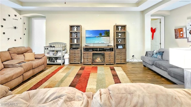 living area with a glass covered fireplace, arched walkways, and wood finished floors