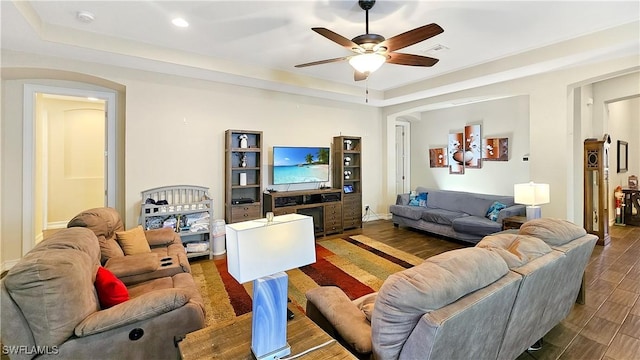 living area featuring ceiling fan, a raised ceiling, wood finished floors, and visible vents