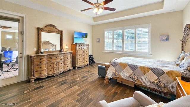 bedroom with wood finish floors, baseboards, ceiling fan, and a tray ceiling