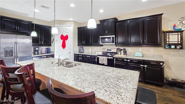 kitchen with visible vents, dark wood finished floors, dark cabinets, stainless steel appliances, and a sink