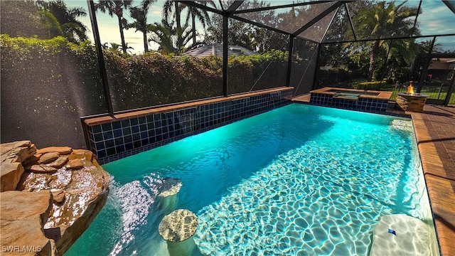 outdoor pool featuring glass enclosure, a patio area, and an in ground hot tub