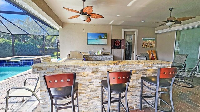 exterior space with glass enclosure, ceiling fan, an outdoor bar, and a pool with hot tub