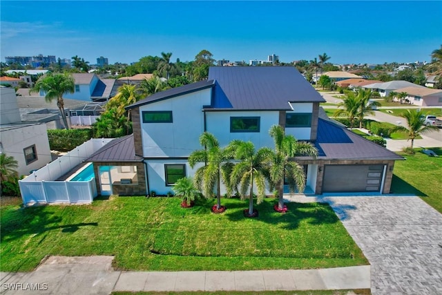 contemporary home with decorative driveway, a standing seam roof, metal roof, and a front lawn