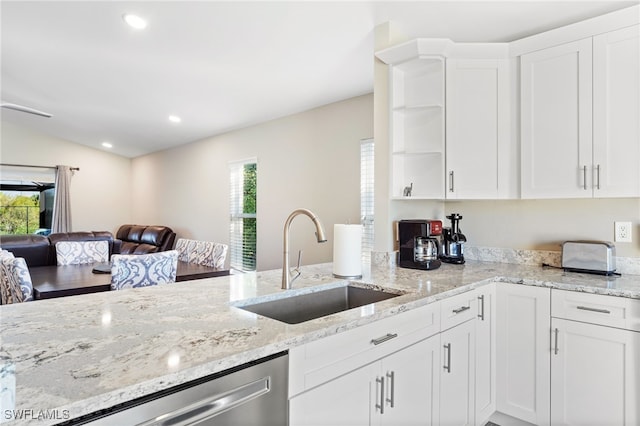 kitchen with light stone counters, white cabinetry, and sink