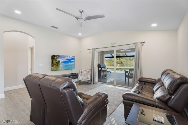 living room with ceiling fan, vaulted ceiling, and light wood-type flooring