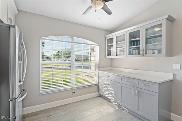 kitchen with gray cabinetry, ceiling fan, stainless steel fridge with ice dispenser, light hardwood / wood-style flooring, and vaulted ceiling