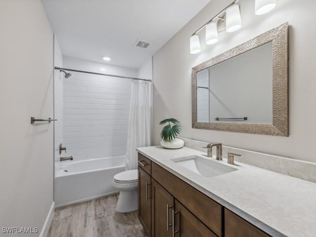 full bath featuring visible vents, toilet, wood finished floors, shower / bathtub combination with curtain, and vanity