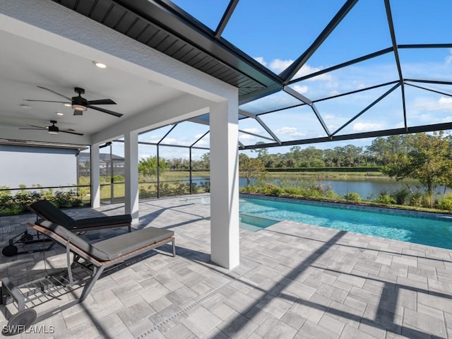 outdoor pool with glass enclosure, a patio area, ceiling fan, and a water view