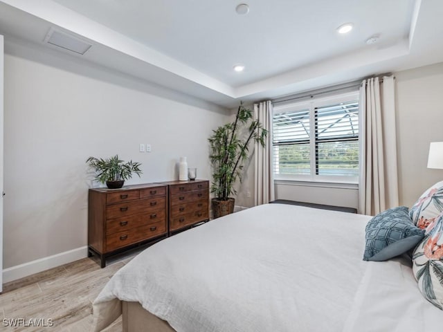 bedroom with recessed lighting, a raised ceiling, light wood-style flooring, and baseboards