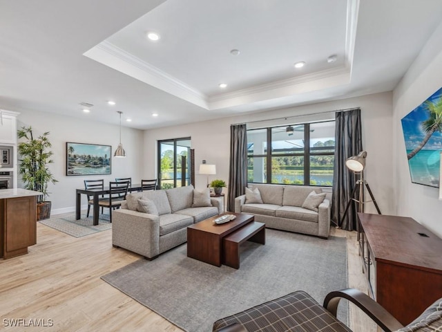 living room with a raised ceiling, crown molding, and light wood-type flooring