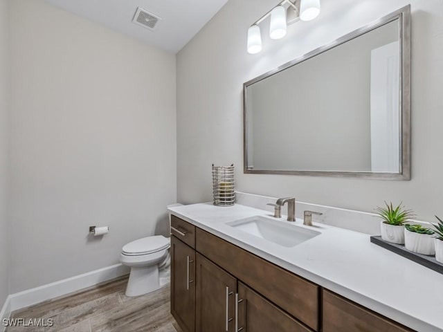 bathroom with hardwood / wood-style floors, vanity, and toilet