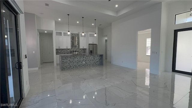 kitchen featuring light stone counters, white cabinets, stainless steel fridge with ice dispenser, a kitchen island, and hanging light fixtures