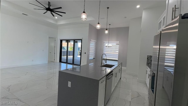 kitchen featuring sink, hanging light fixtures, stainless steel appliances, a kitchen island with sink, and white cabinets