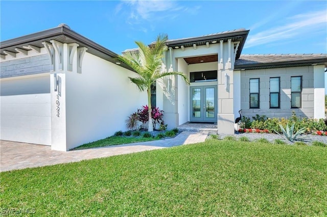 doorway to property with french doors, a yard, and a garage