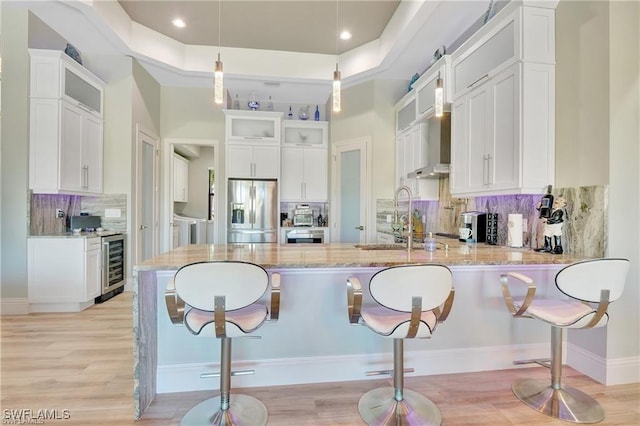 kitchen with wine cooler, white cabinets, hanging light fixtures, and stainless steel refrigerator with ice dispenser