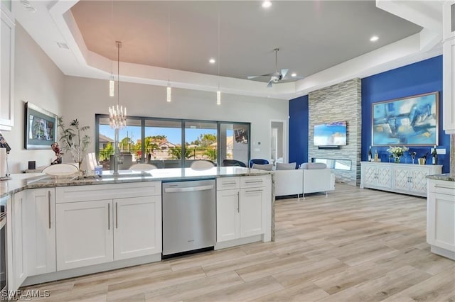 kitchen featuring a raised ceiling, white cabinetry, dishwasher, and light stone counters