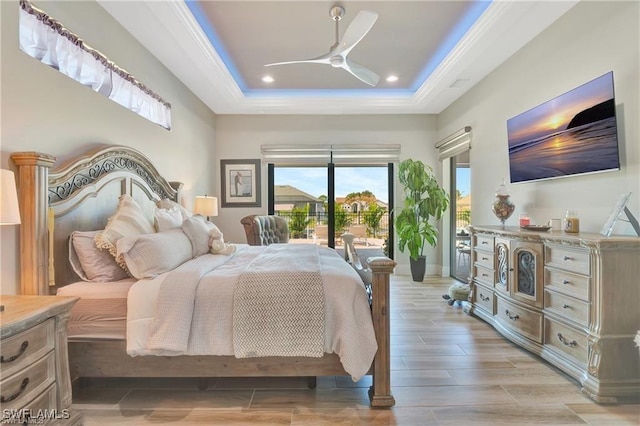 bedroom featuring ceiling fan, access to exterior, and a tray ceiling