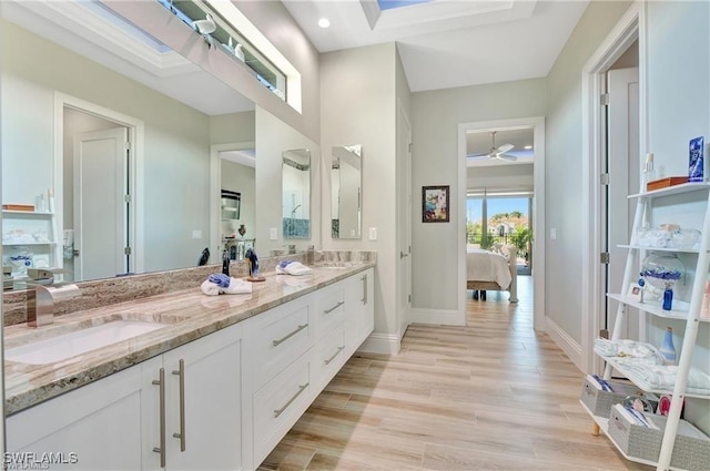 bathroom with vanity, ceiling fan, wood-type flooring, and a skylight