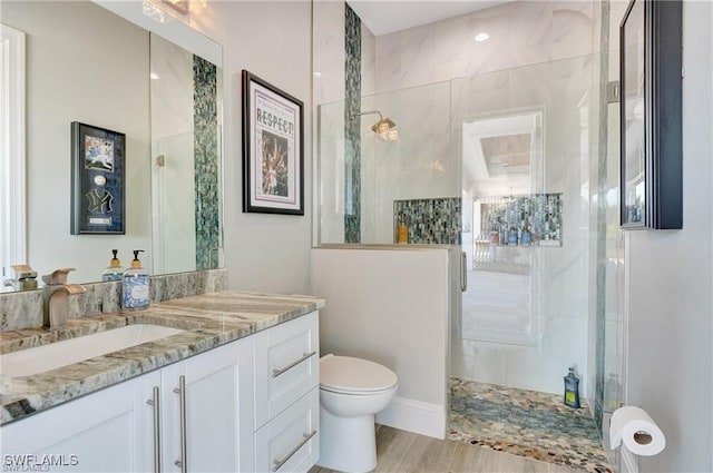 bathroom with walk in shower, vanity, and toilet