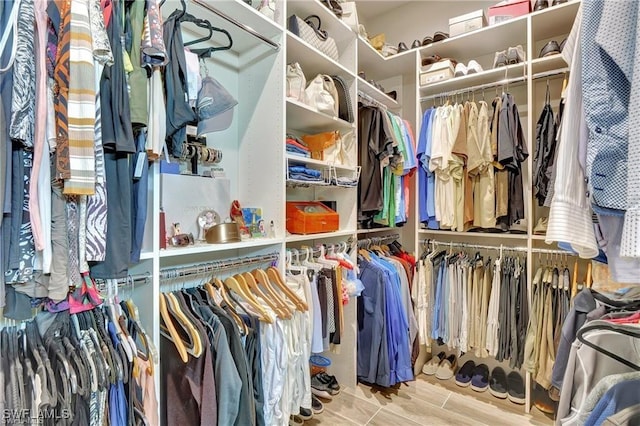 walk in closet with light hardwood / wood-style flooring