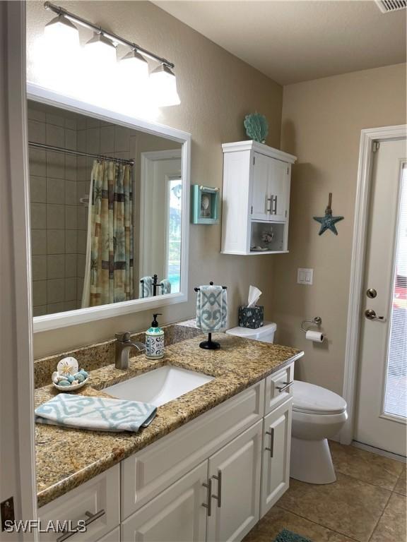 bathroom with tile patterned floors, plenty of natural light, vanity, and toilet