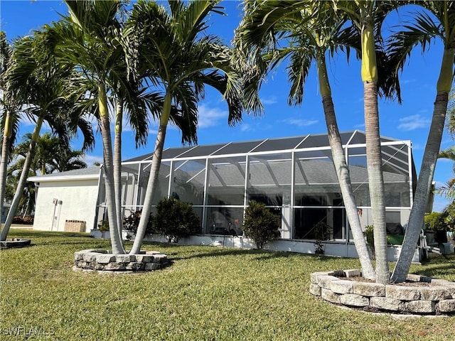 back of property featuring a yard and glass enclosure