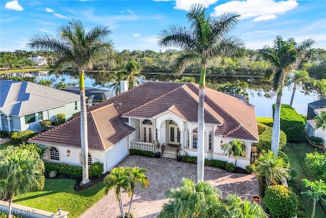 mediterranean / spanish-style home featuring a front lawn, french doors, and a water view