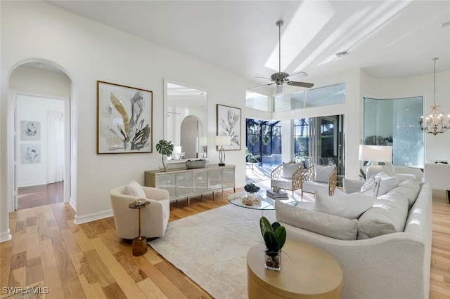 living room with ceiling fan with notable chandelier and light hardwood / wood-style flooring