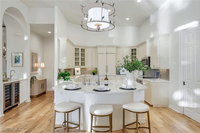 kitchen featuring pendant lighting, light hardwood / wood-style floors, a kitchen island with sink, and paneled built in refrigerator